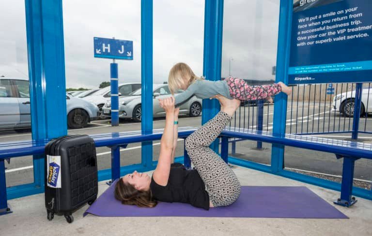 Mum and young daughter doing a yoga pose with child on mum's feet