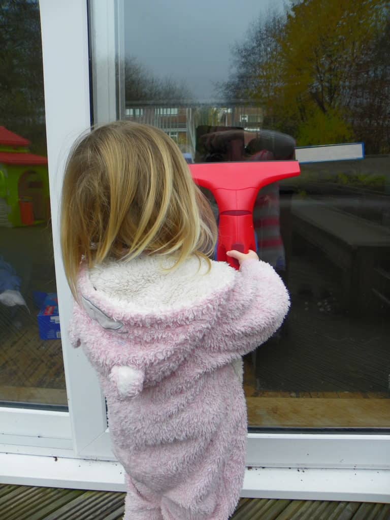 Toddler using a Window Vacuum Cleaner on a patio door
