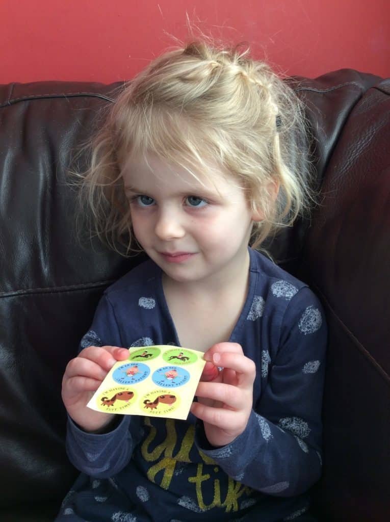 Little girl showing a sheet of colourful stickers