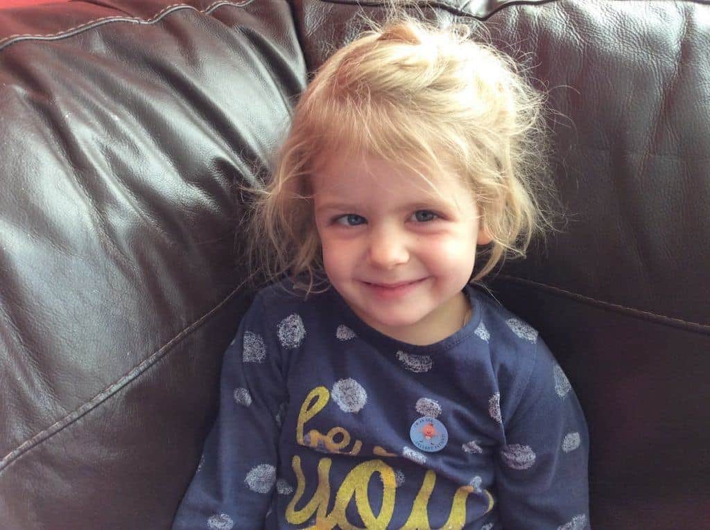 Little girl sitting on a sofa smiling