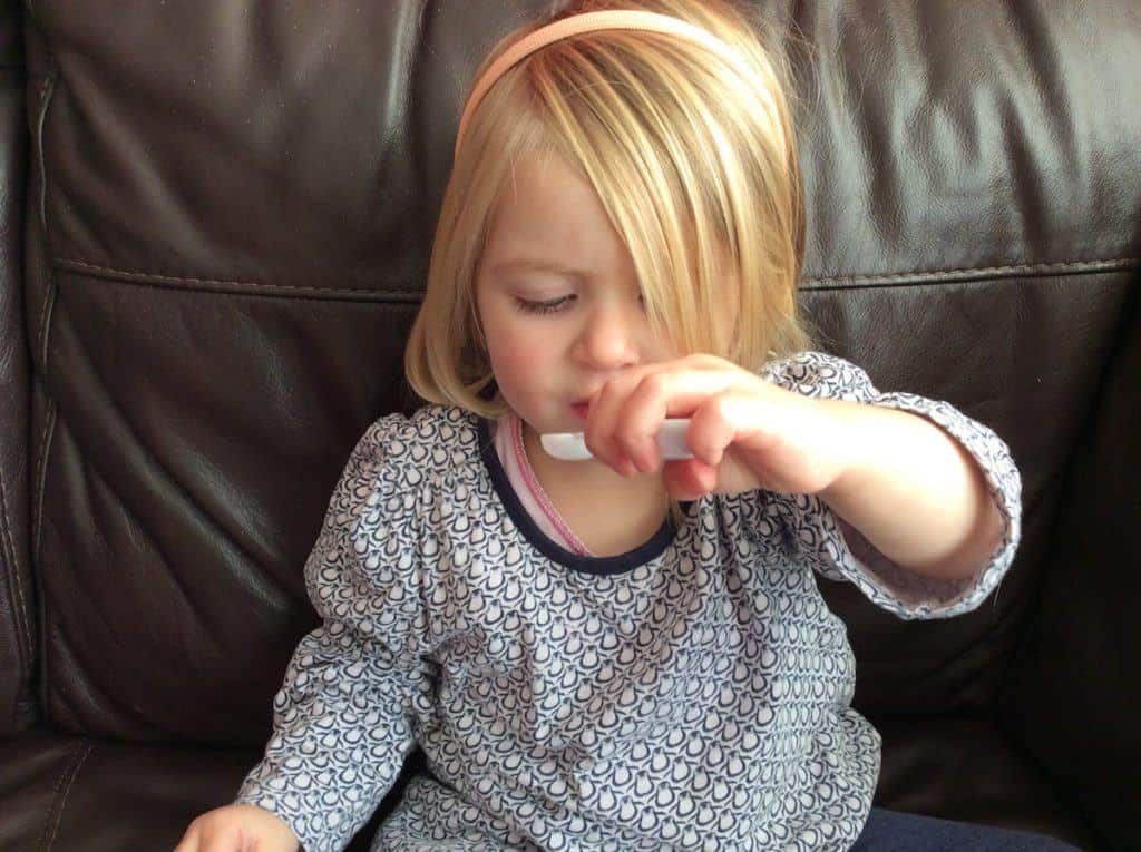 toddler with white medicine spoon in her hand