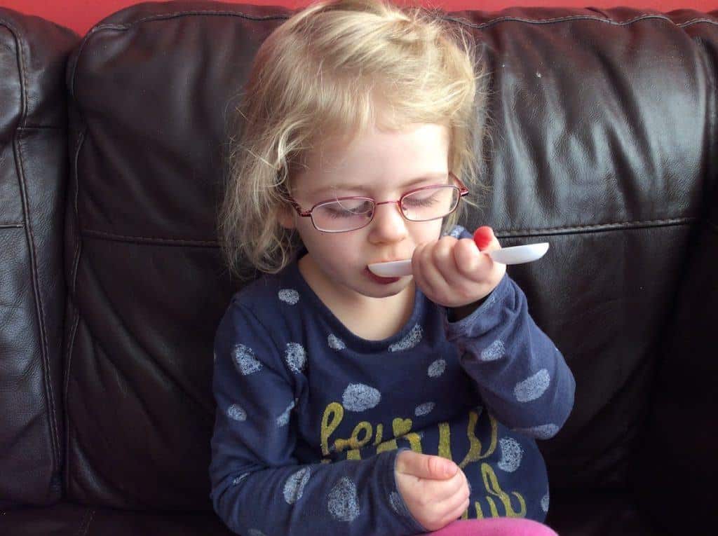 Little girl with medicine spoon in her mouth