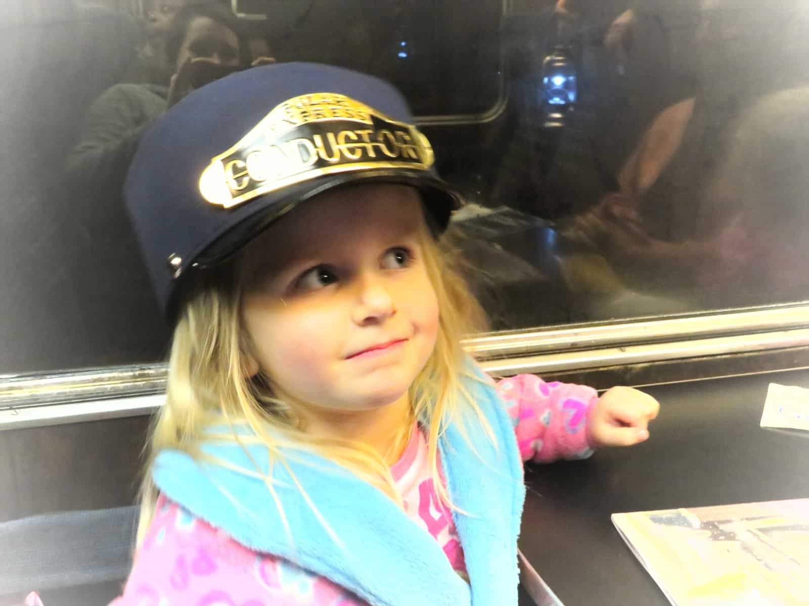 Little girl in a dressing gown wearing the polar express conductor's hat