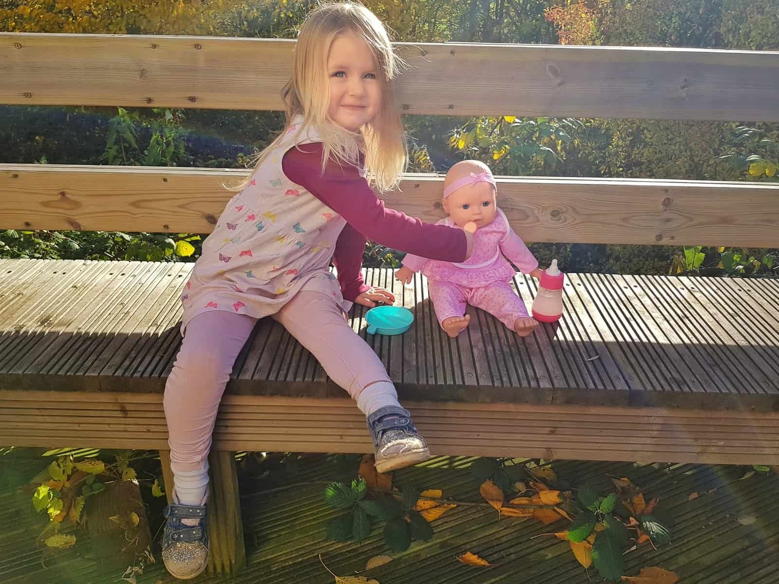 3 year old girl feeding food to doll