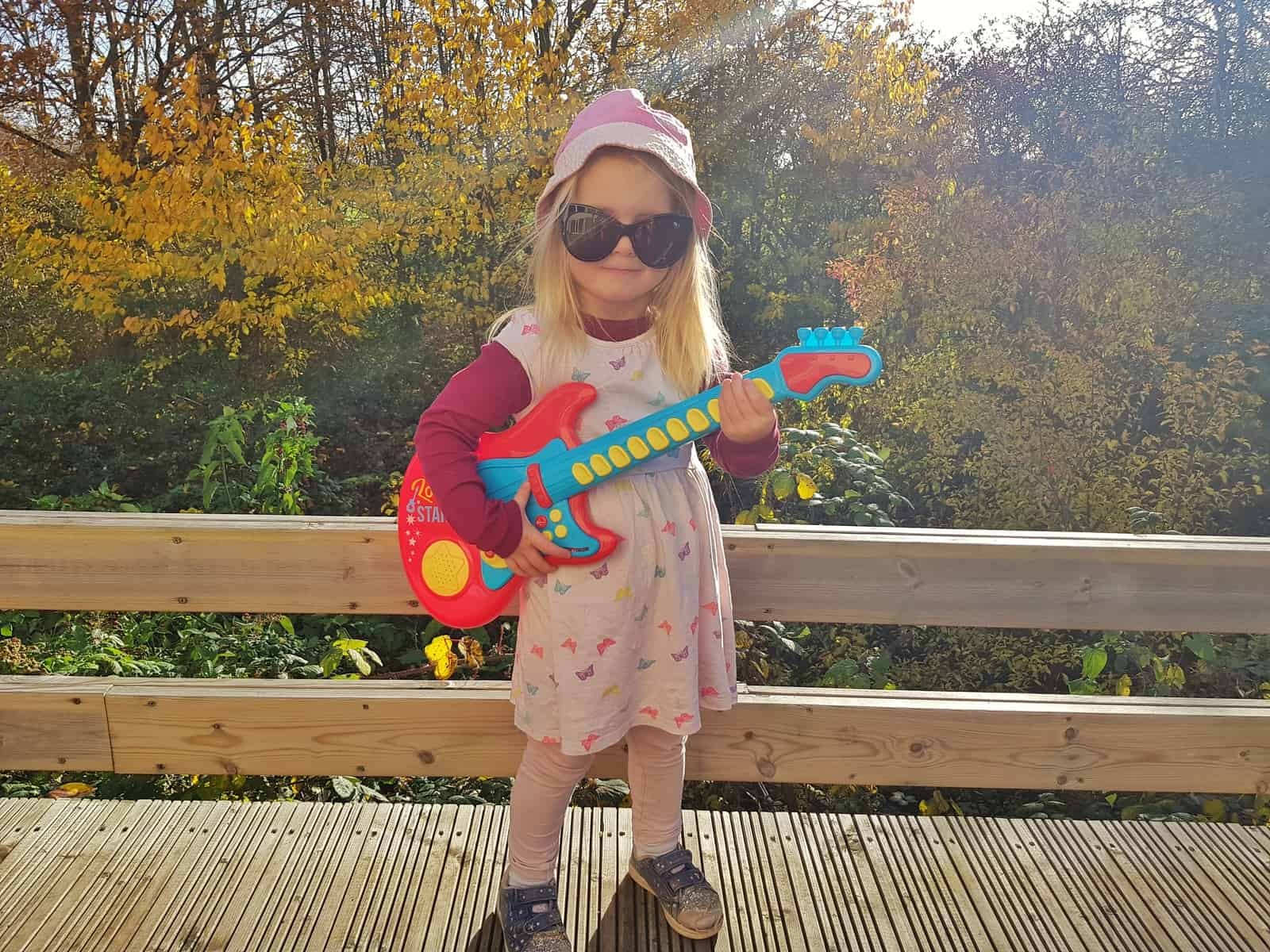 3 year old girl with red and blue plastic guitar