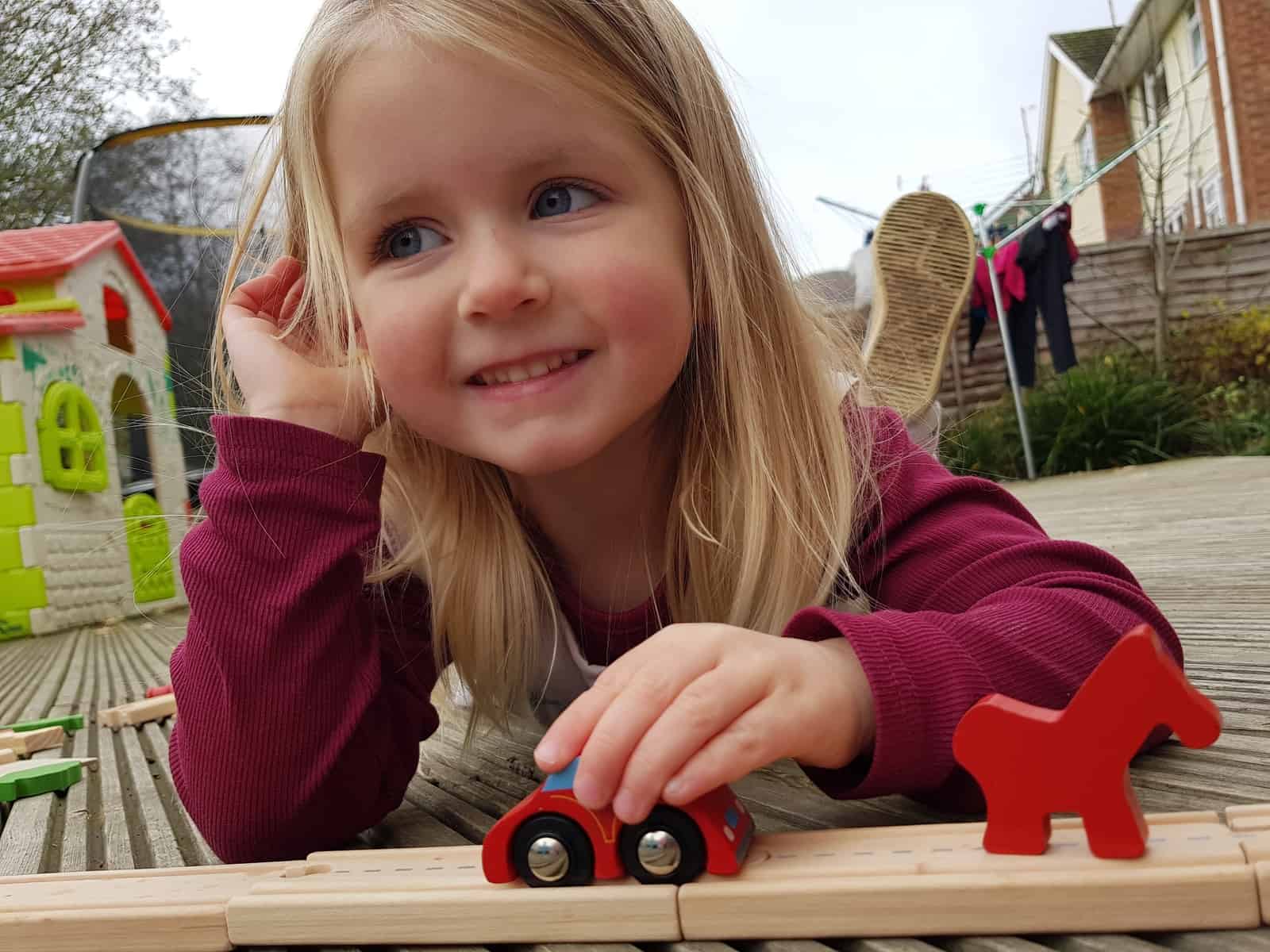 3 year old girl with toy car on a track