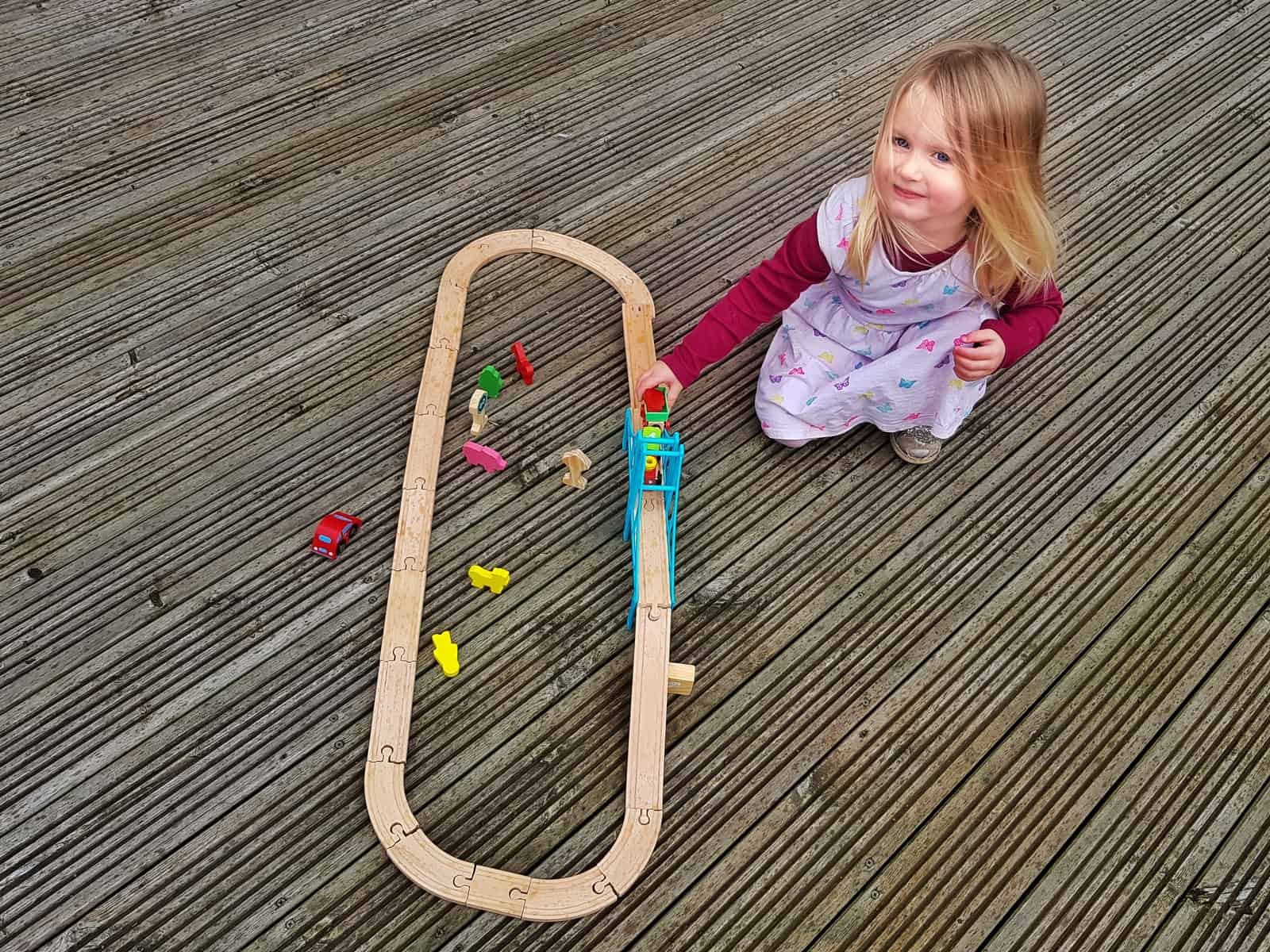 3 year old girl with toy trains on track