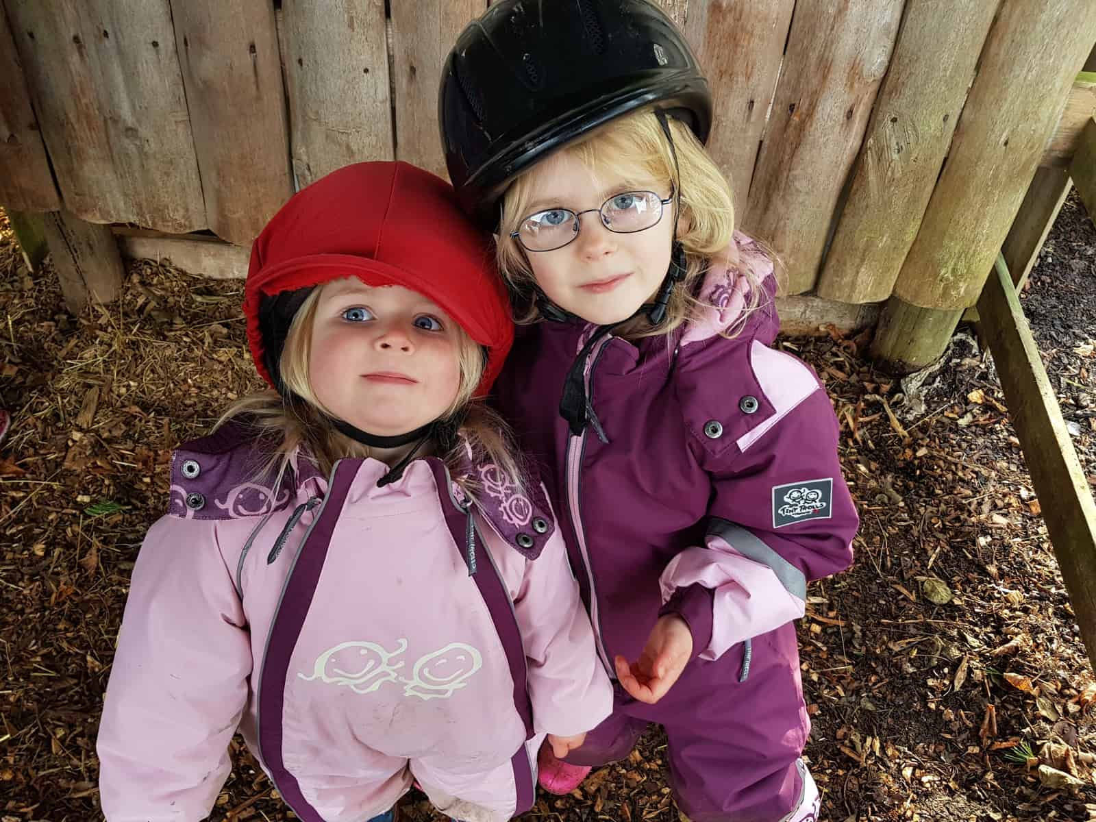 Two little girls with riding hats on at Newbridge Farm Park near Ledbury, Herefordshire in the West Midlands