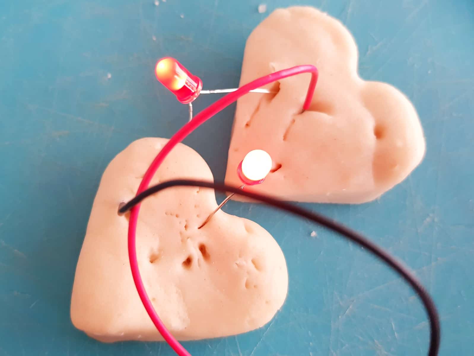 Two play dough hearts creating a circuit from with STEM science kit