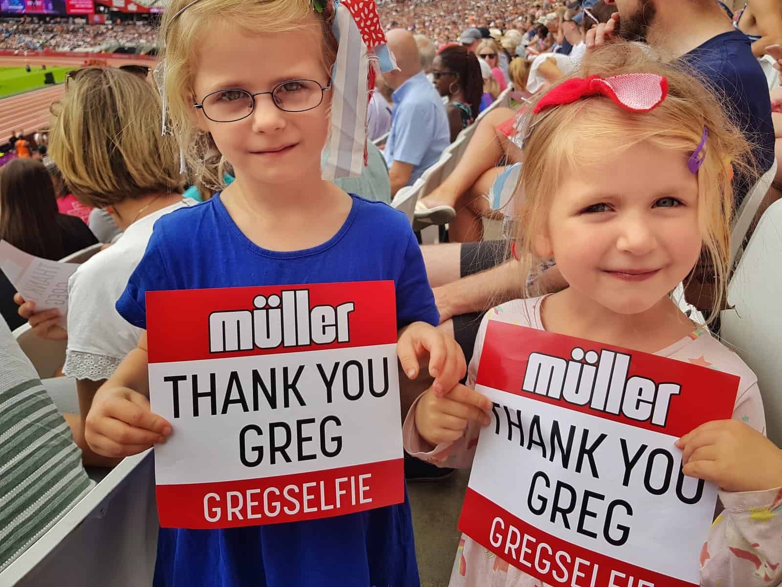 Two girls holding Thank you Greg signs at the Muller Anniversary Games