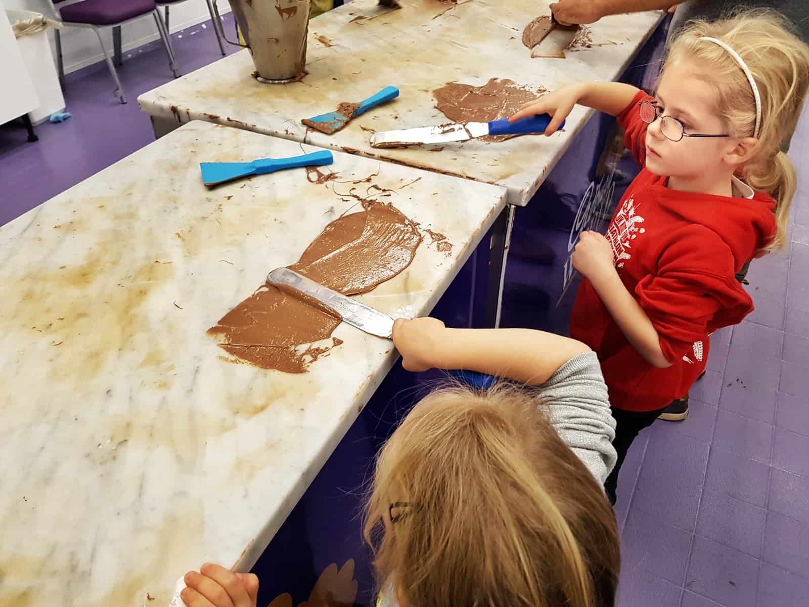 A family day out at Cadbury World Birmingham two girls tempering chocolate 