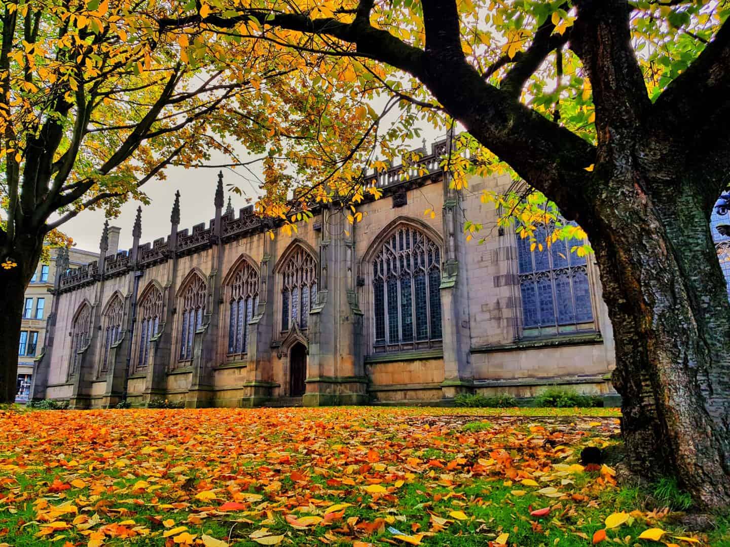 Manchester Cathedral in autumn with leaves in the foreground
