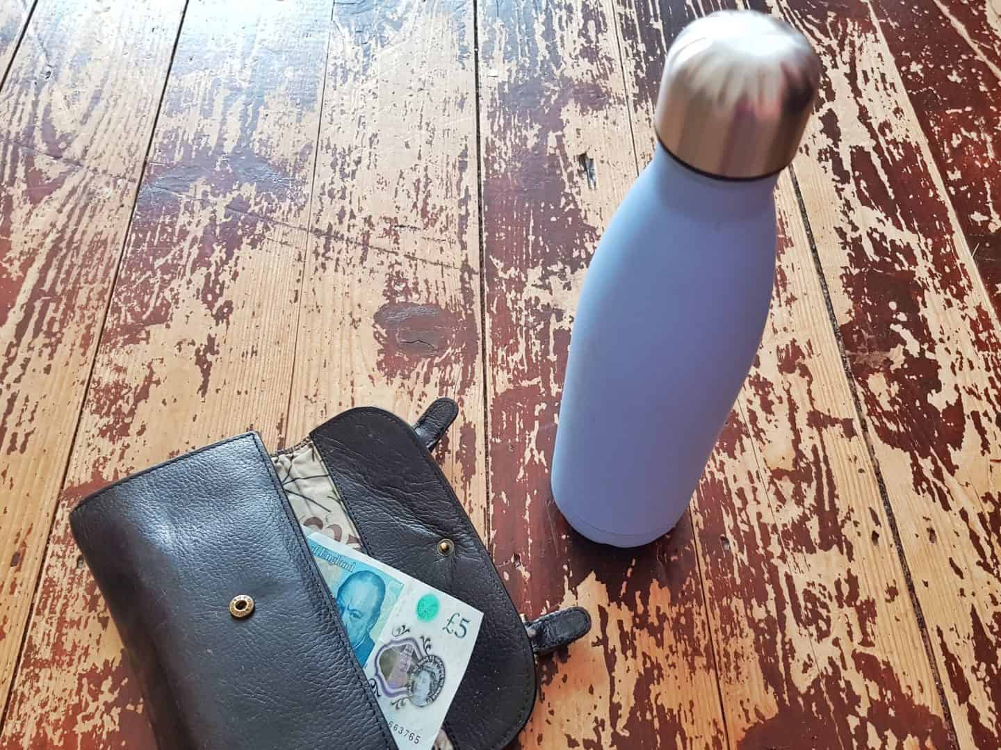 debt consolidation photo purse with fiver hanging out and flask beside