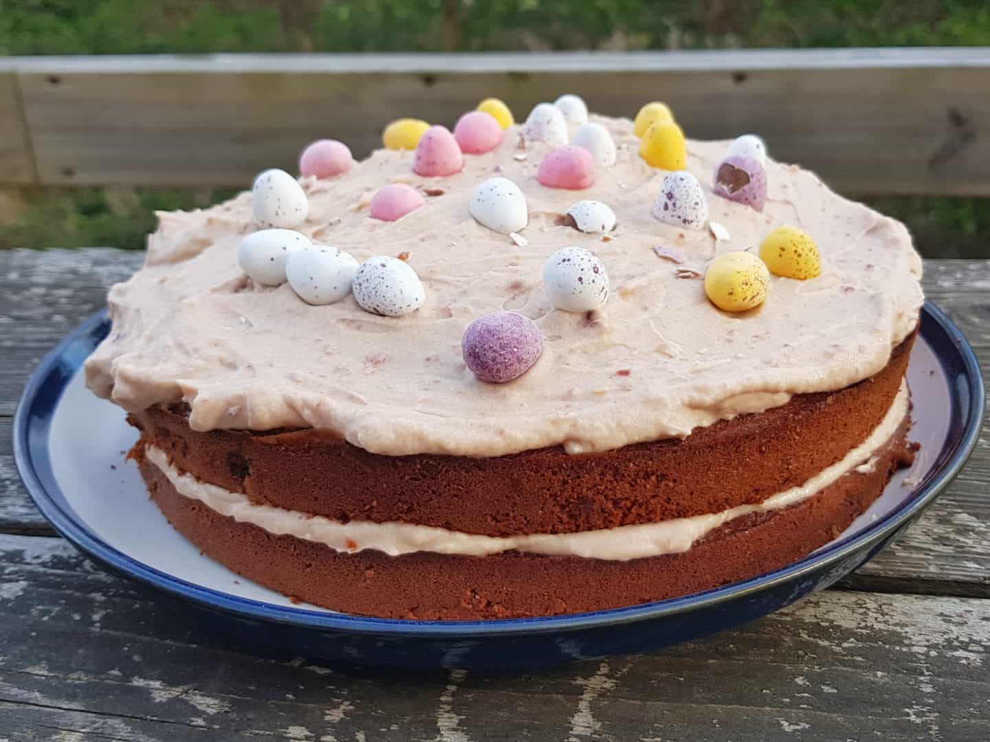 Chocolate cake with icing in centre and on top and mini eggs decorating the top