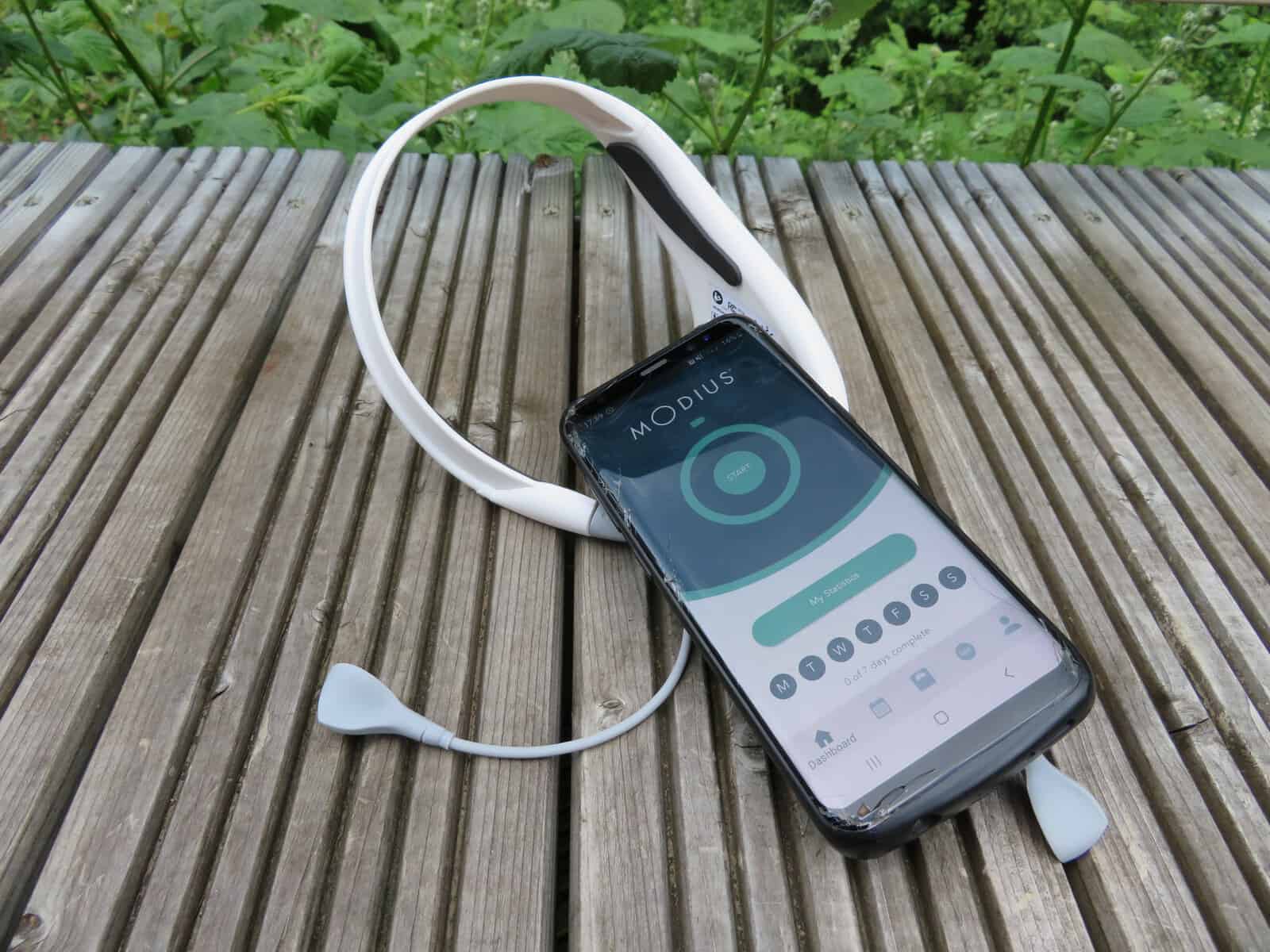 Modius health headset next to mobile phone with Modius app