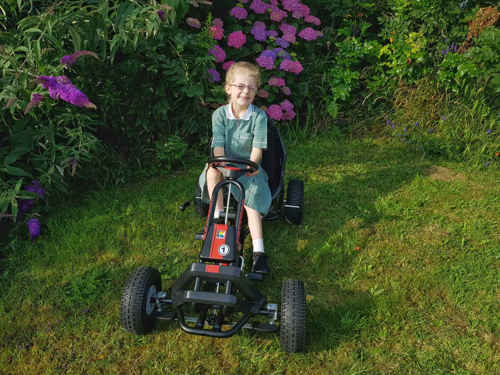 Girl riding Kettler Barcelona Air Go Kart front view with flowers behind