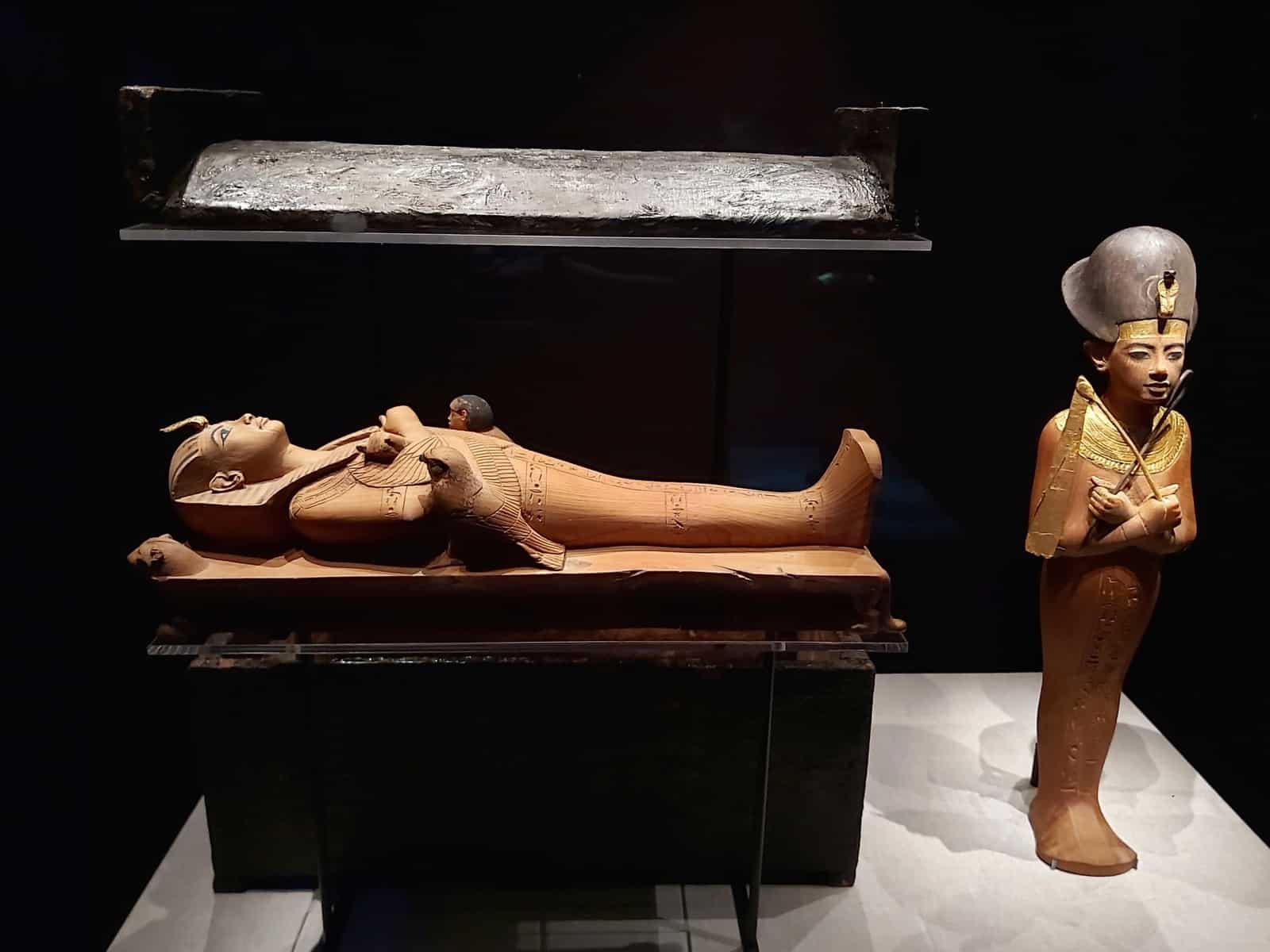 Two miniature statues. One is of Tutankhamun lying down as per the death mask. The other is standing up.