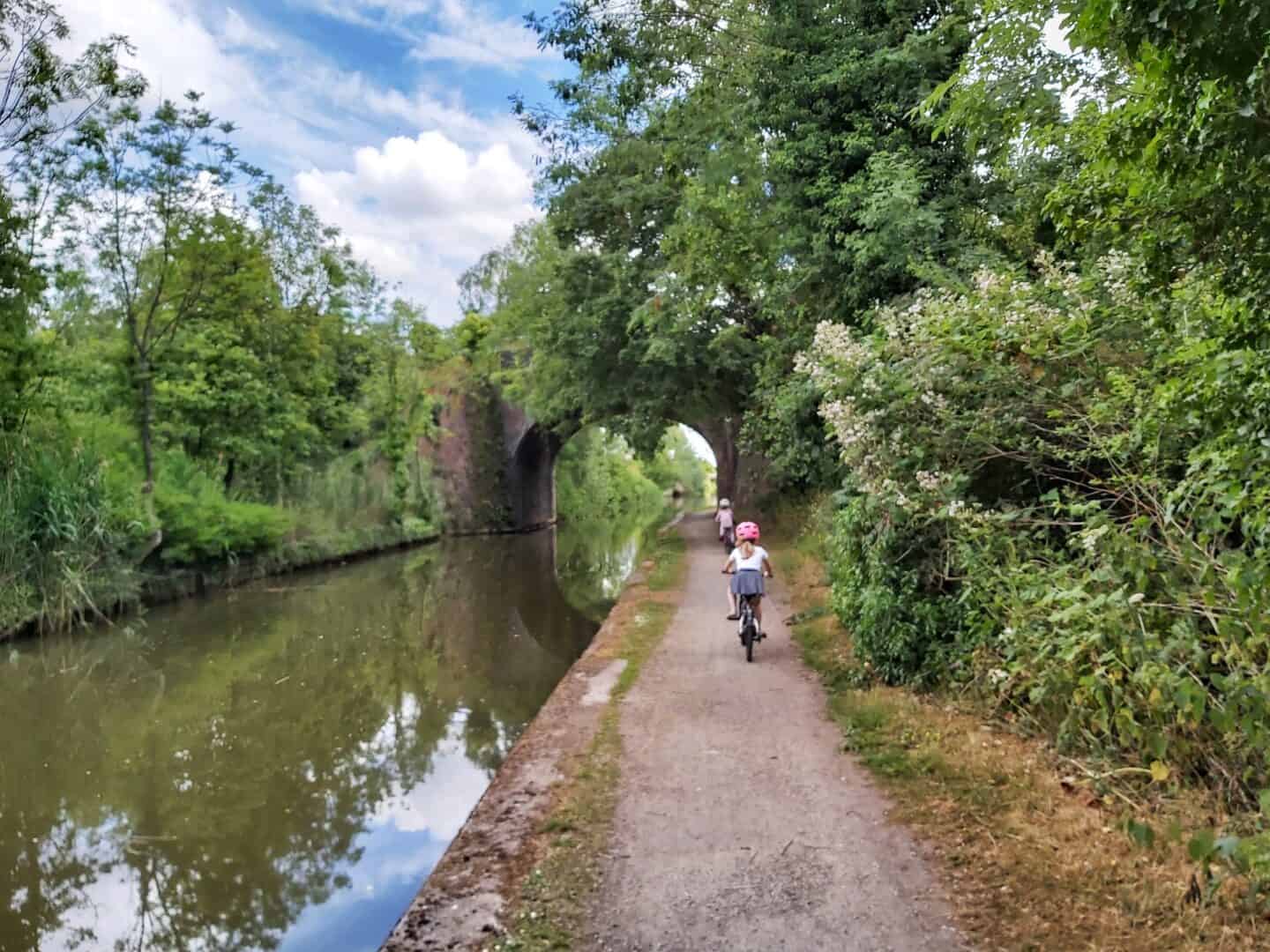 Child cycling down a canal towpath