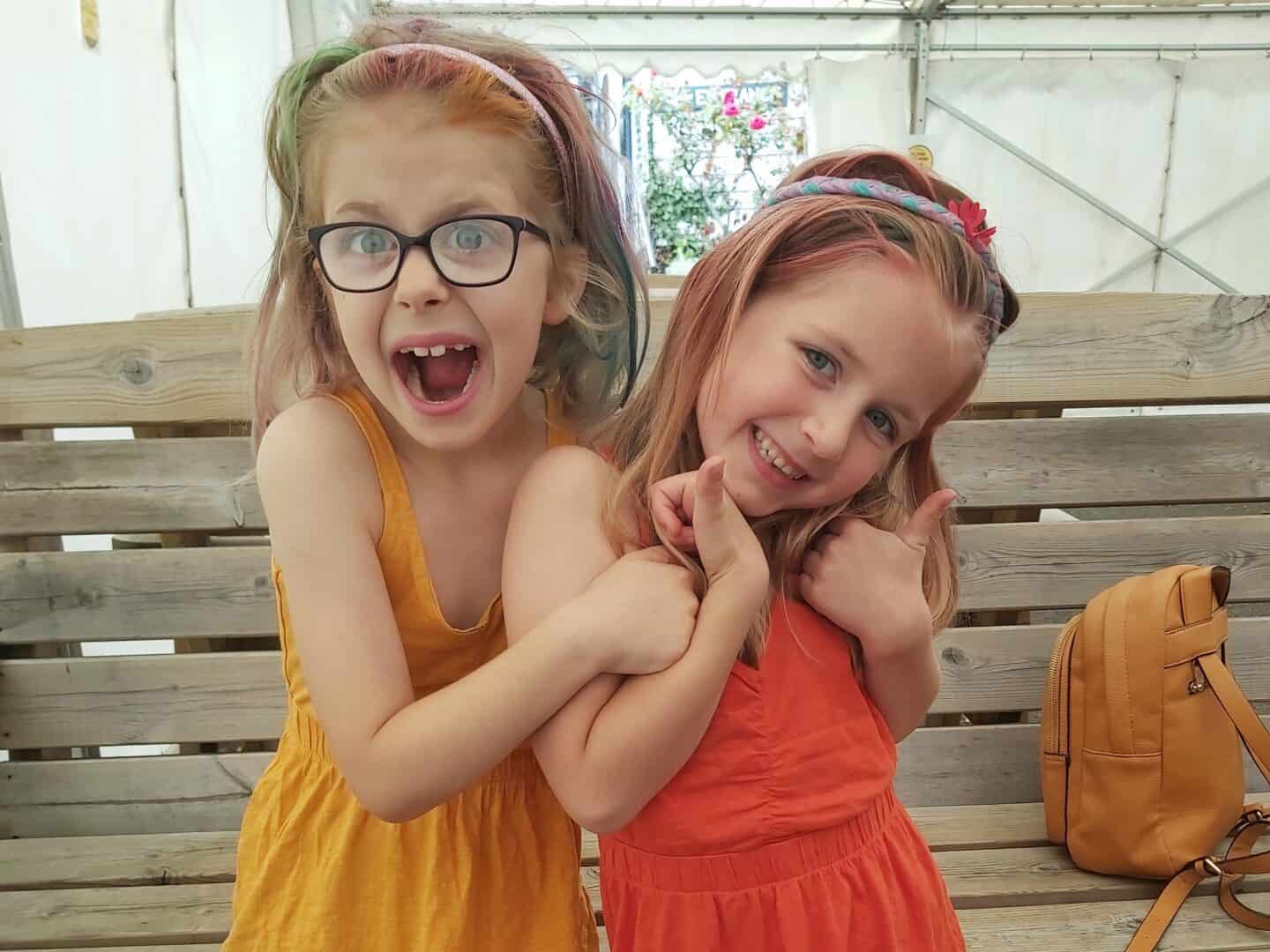 Two girls in yellow and orange dresses with rainbow hair