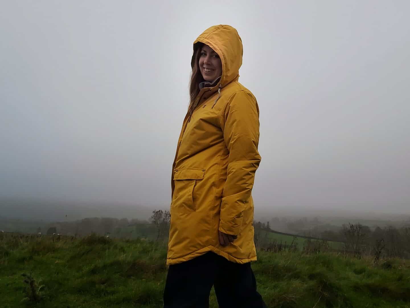 Standing side on in Lighthouse Clothing sunrise Iona raincoat on a foggy day