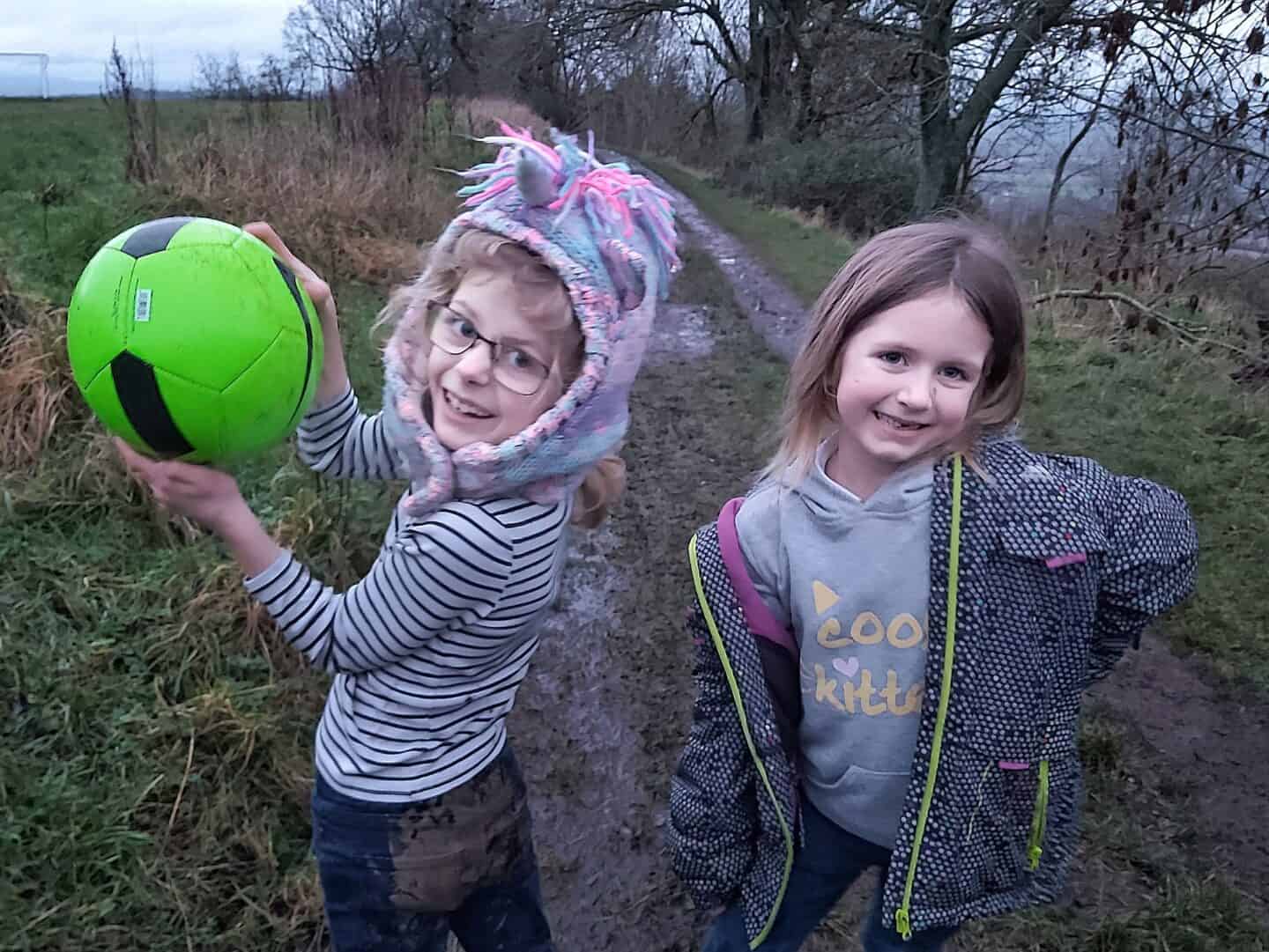 birthday gifts by age: Two girls covered in mud showing off the football they received for Christmas