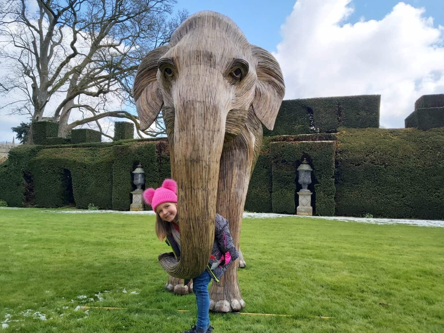Little girl peeping out from behind elephant sculpture