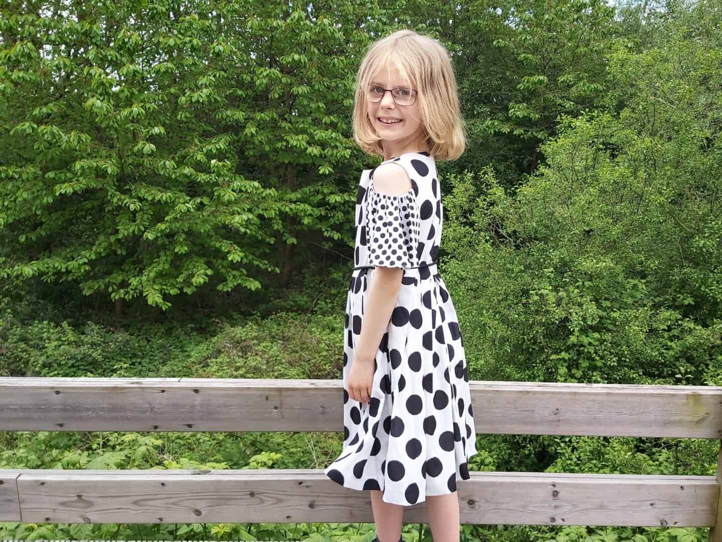 Little girl in monochrome midi dress with trees behind 