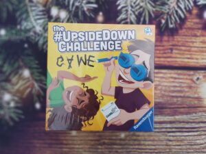 Ravensburger Upside Down Challenge game photographed on wooden background with pine branches and Christmas lights