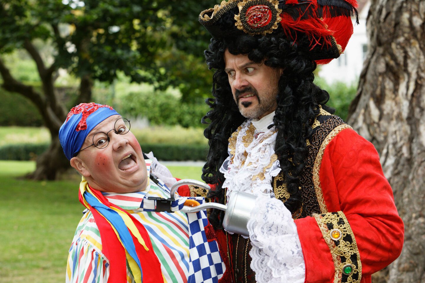 Peter Pan pantomime at Malvern Theatres Captain Hook and Smee pictured outside next to a tree with grass in the background
