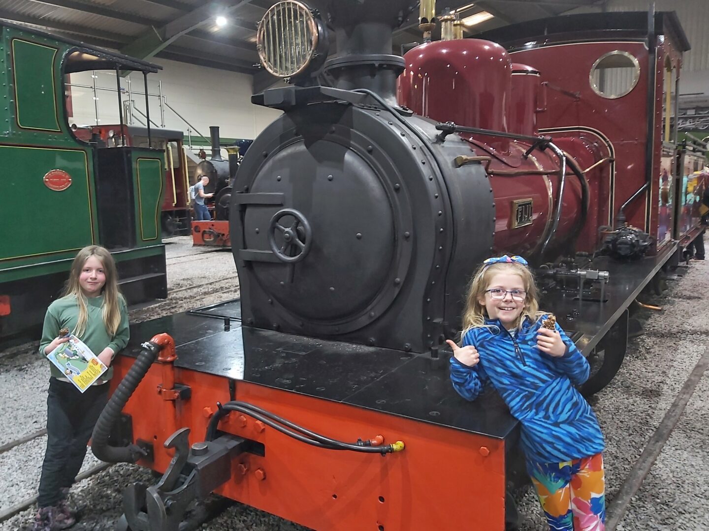 Two girls standing either side of a steam engine at Statfold Barn museum in Tamworth West Midlands