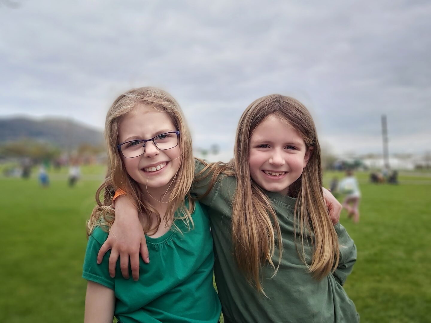 Two girls with arms around each other with grass and malvern hills in background at Countrytastic at Three Counties Showground