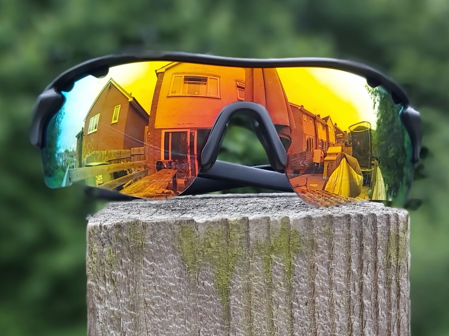sunglasses displayed outdoors with a house reflected in the mirrored lens - sports glasses make great gifts for hikers