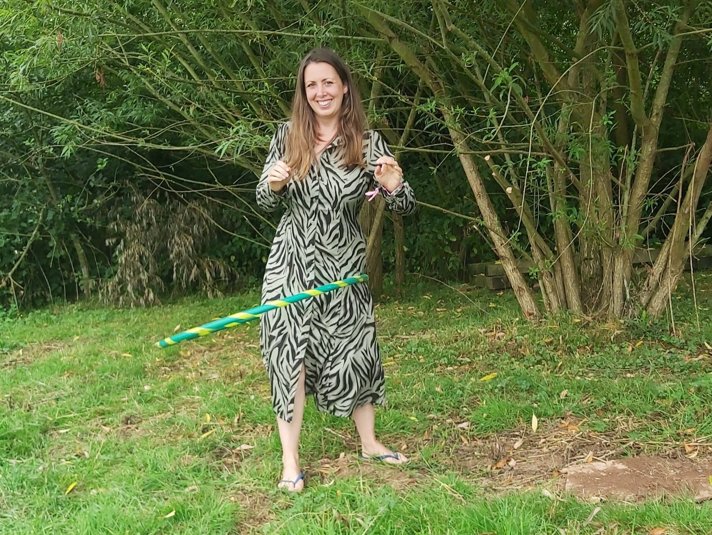 Adult female pictured in a field with tree and hedge behind wearing a Cotton Traders khaki green maxi dress with fern pattern