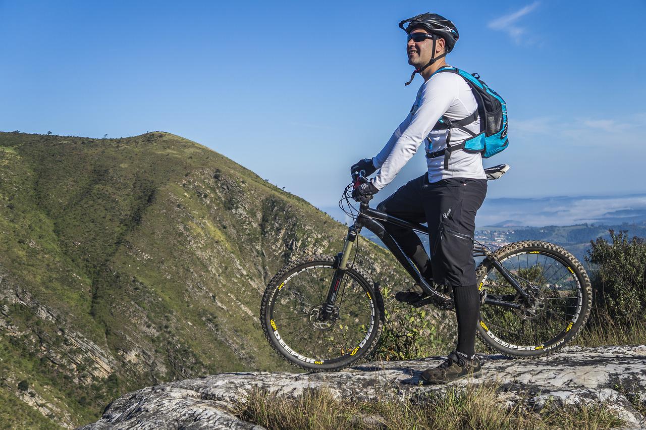 Man on a mountain bike wearing a cycle helmet with mountains in the background