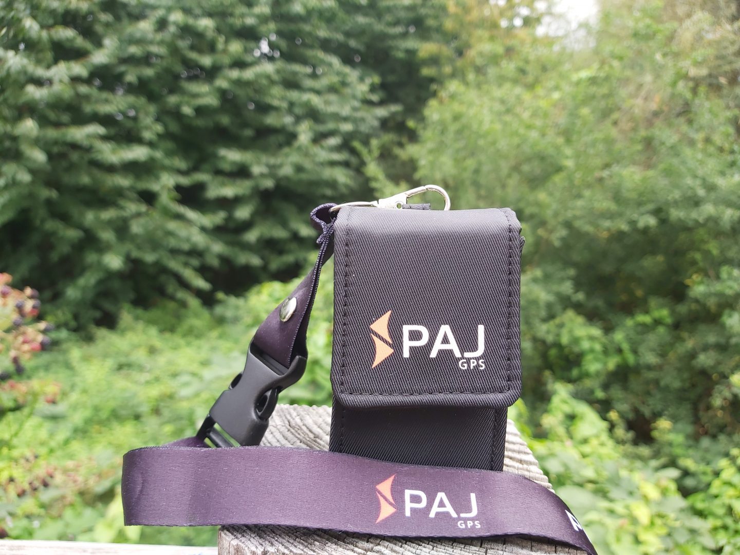 PAJ Easy Finder GPS Tracker in case with lanyard attached with trees in background
