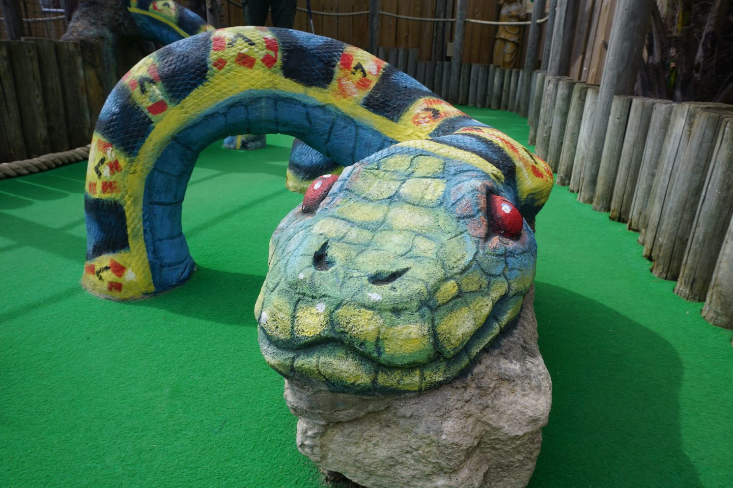 Giant stone snake painted green with red eyes at Lost World Adventure Golf Great Yarmouth