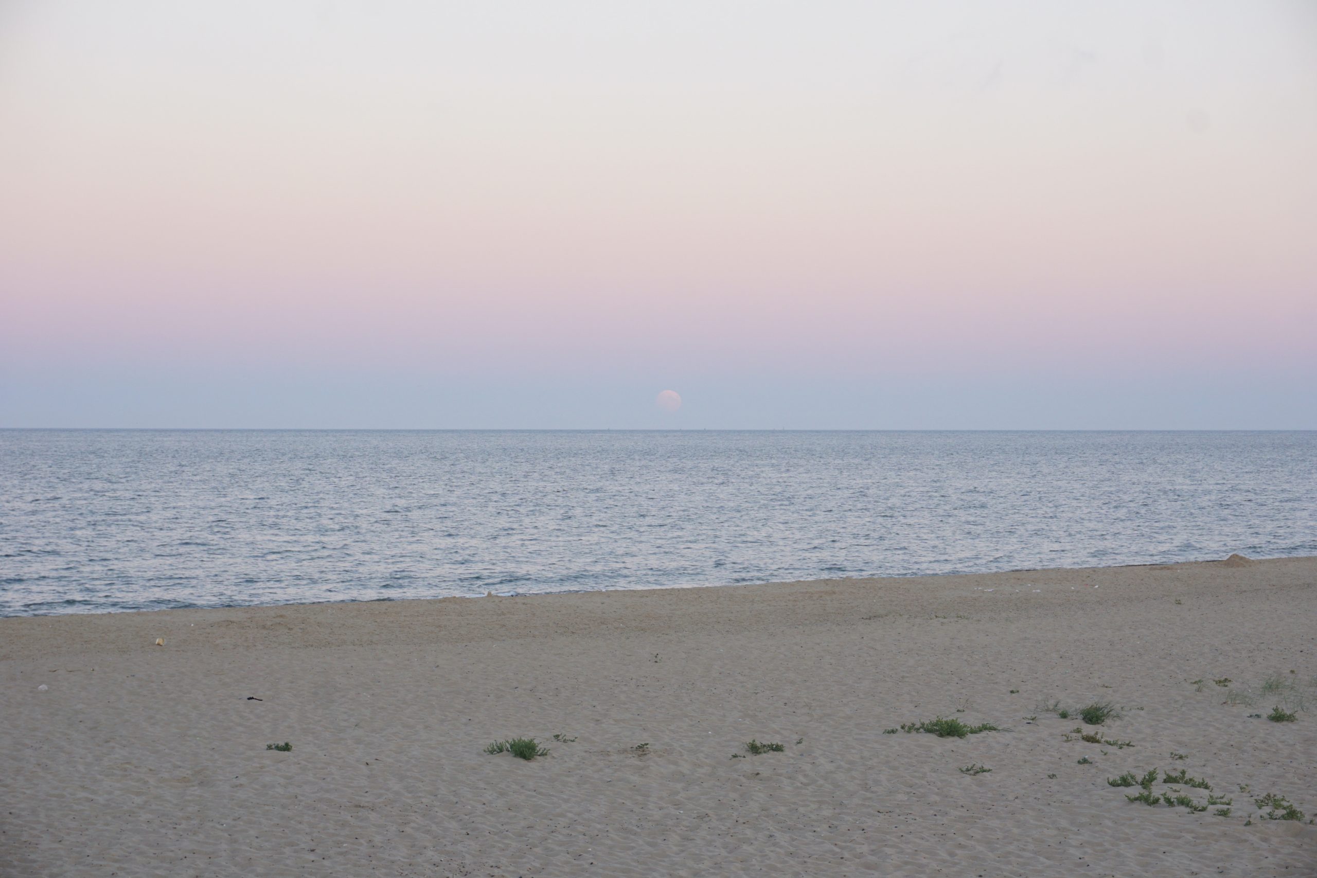 Great Yarmouth Central Beach at dusk with the moon visible in a pink sky above the sea