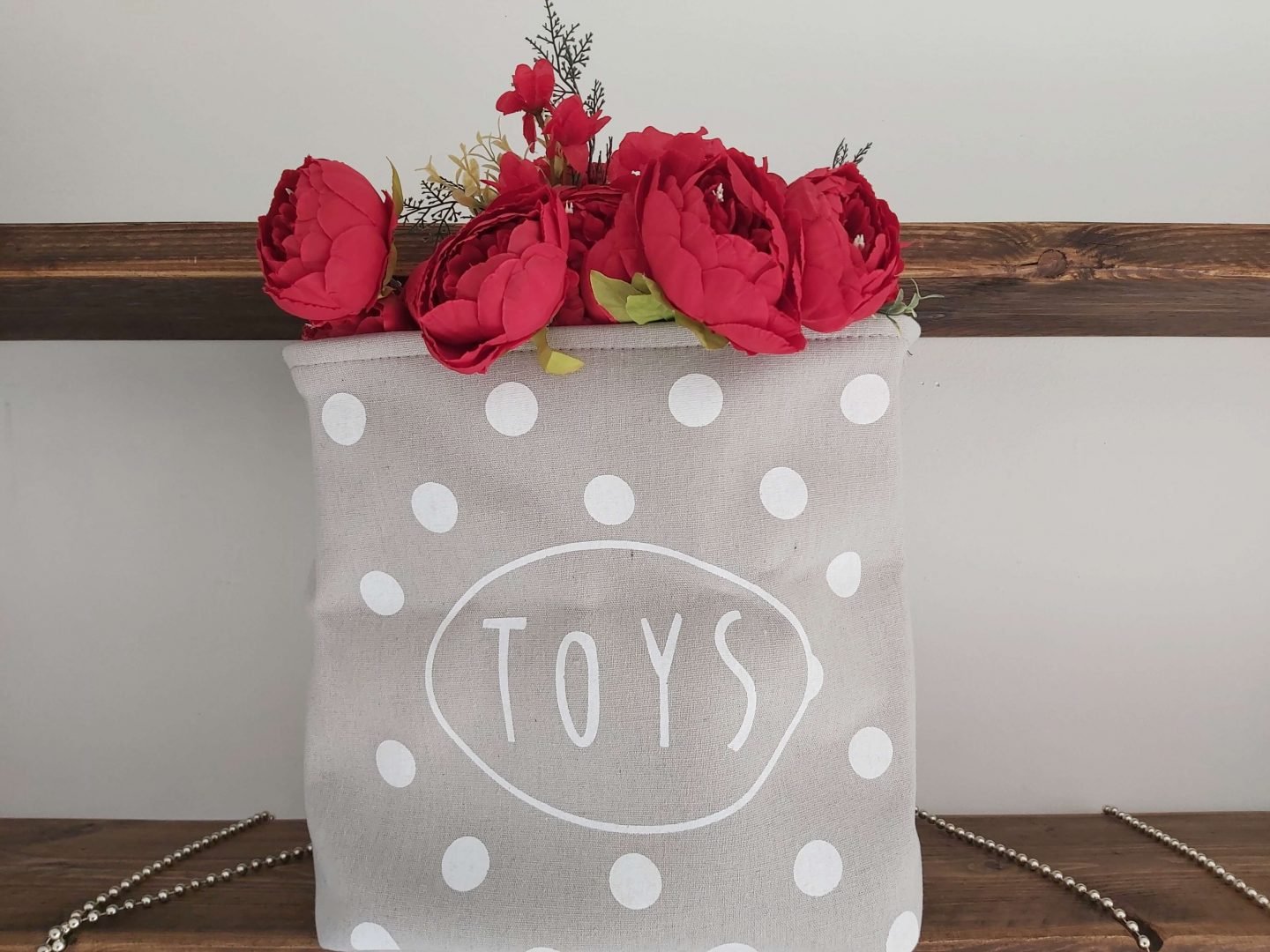 Large grey fabric basket with TOYS written on it and white polka dots for pet toys included in the something you need section of the four gift rule