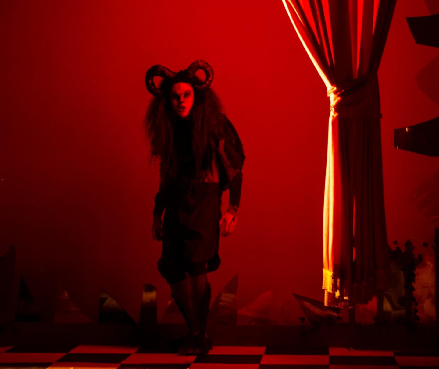 The beast from Beauty and the Beast at the Old Rep Birmingham 2022 against a red background with red curtain in foreground