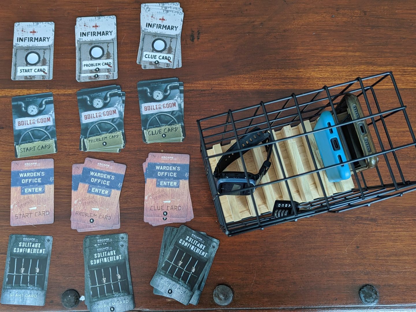 Phone escape room, a traditional toy with puzzle cards laid out next to it and phones locked inside
