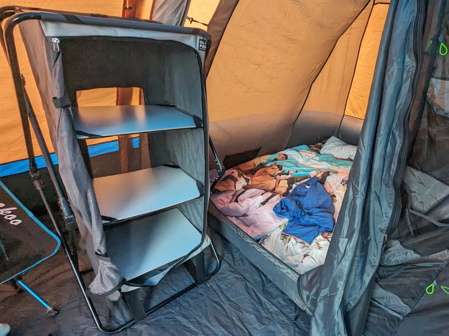 Collapsible storage unit in an awning with bed on the floor beside