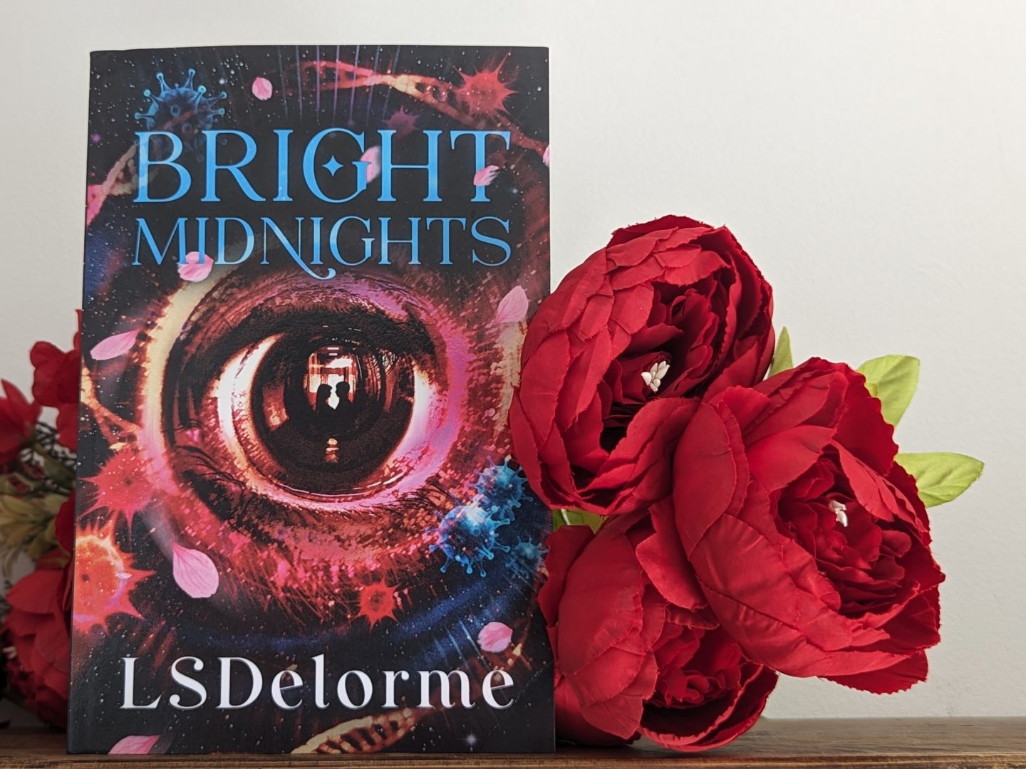 Bright Midnights book with red flowers in front displayed on a wooden shelf
