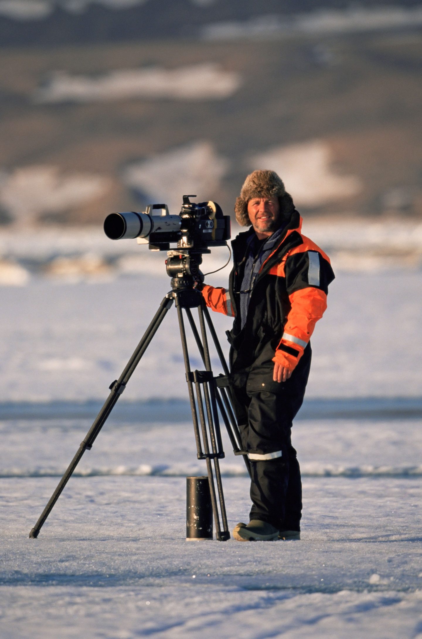 Doug Allan documentary film maker standing on ice with his camera