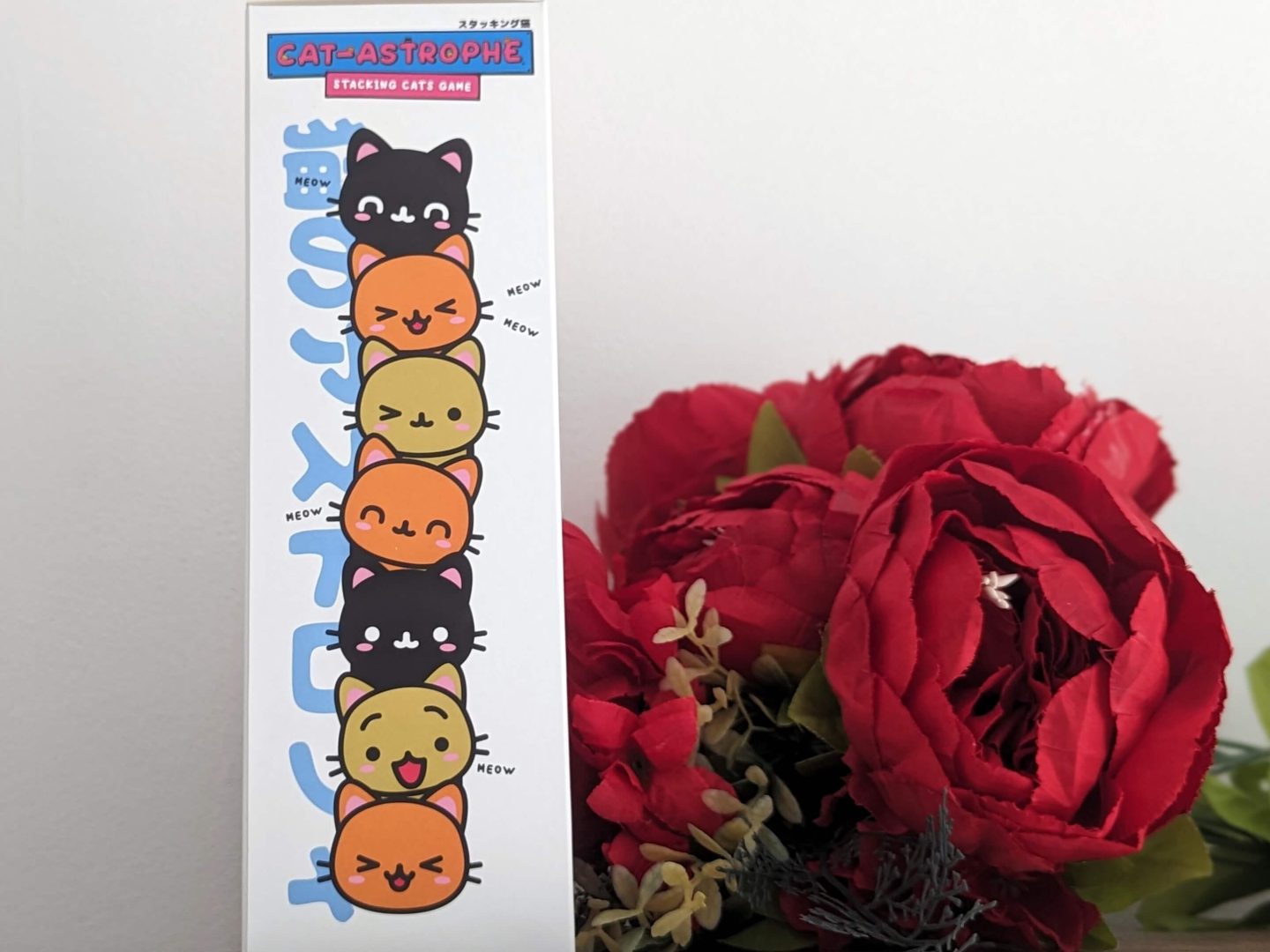 Catastrophe tower game displayed next to red bunch of flowers in front of a white wall