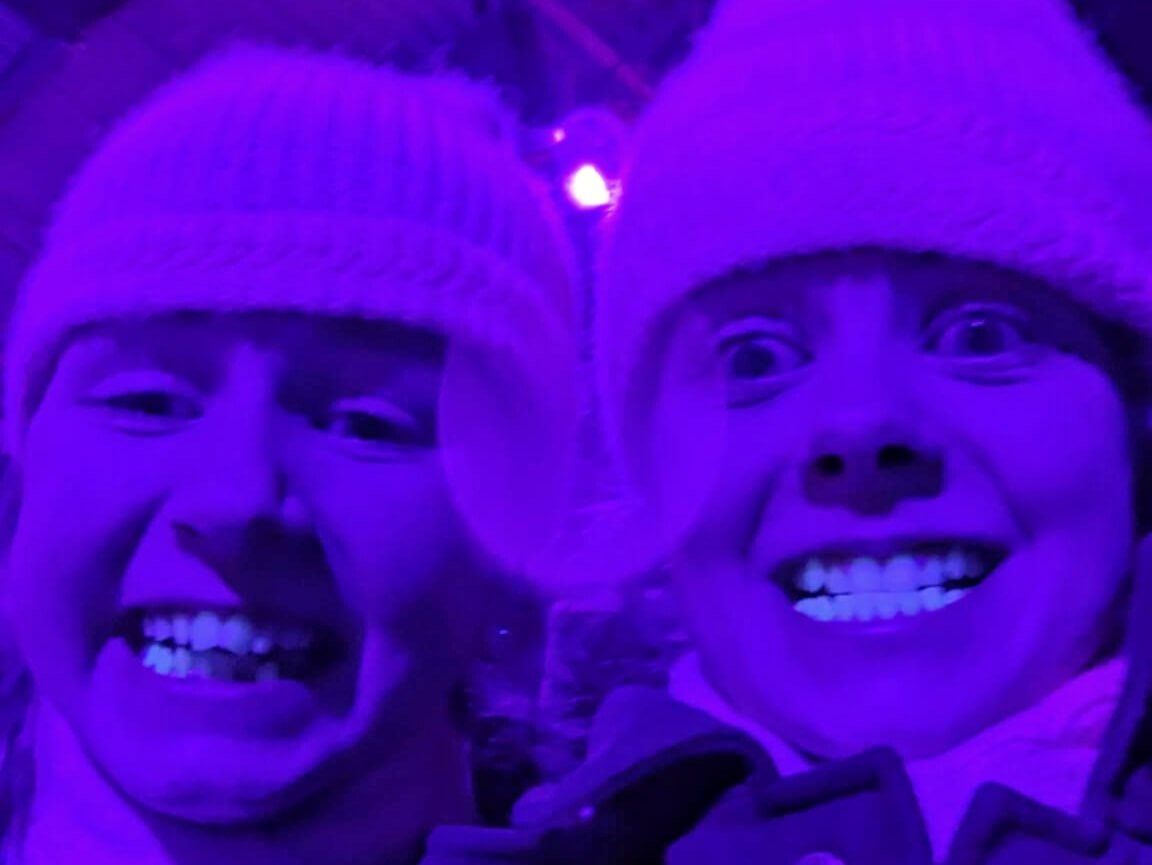 Two girls showing off their UV glowing teeth in the crazy golf at Winter Glow 2024