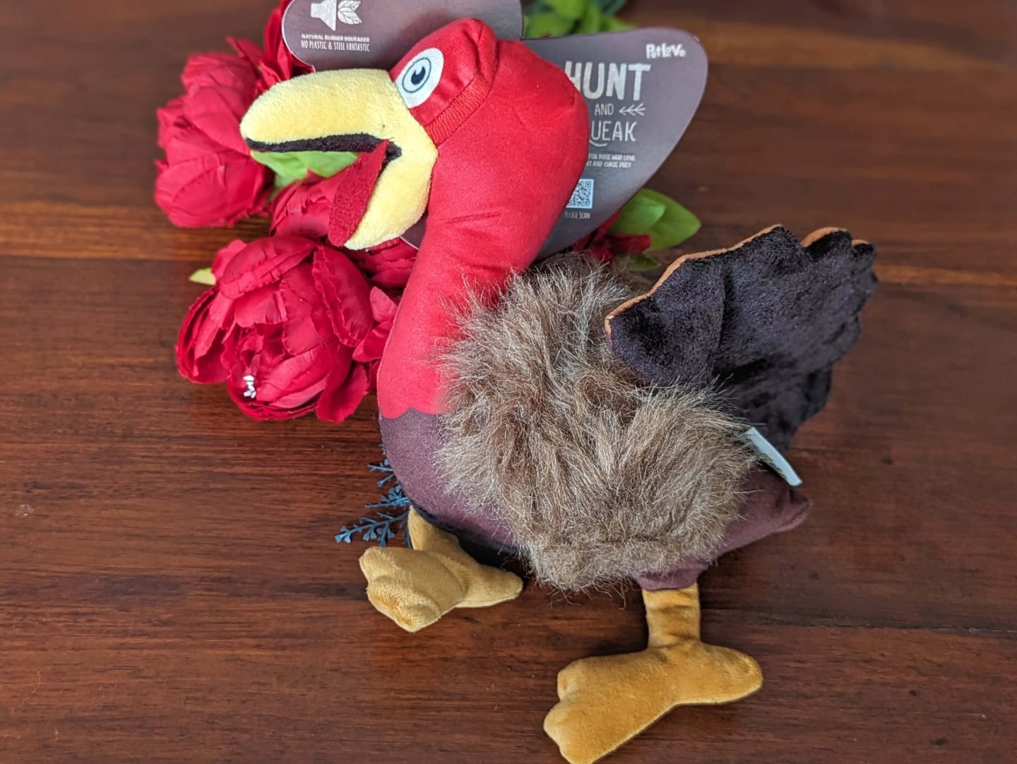 PetLove Hunt n Squeak Wild Turkey toy displayed against a wooden background with red flowers under the turkey's head - part of the pet section of the four gift rule Christmas gift guide