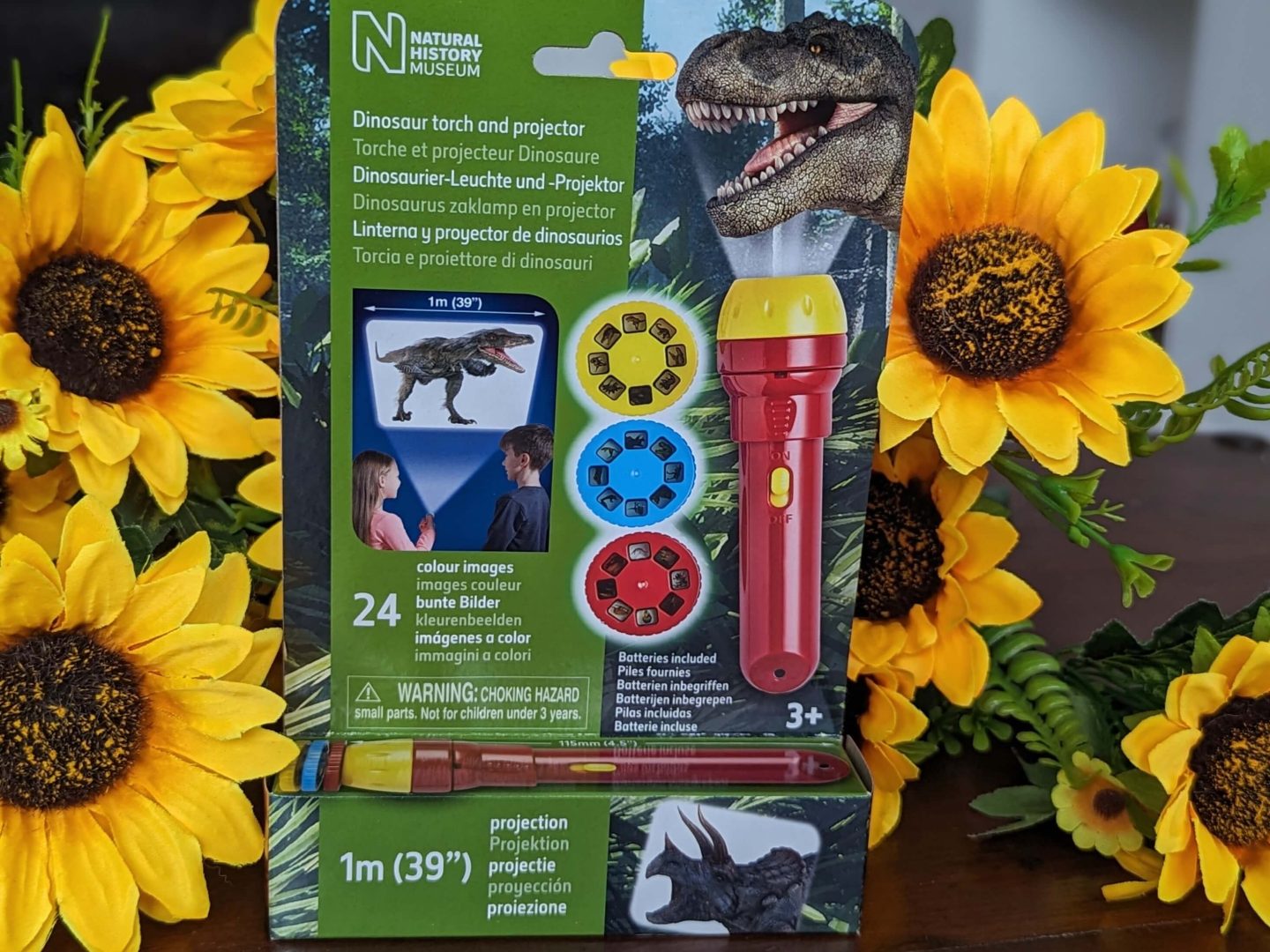 Dinosaur torch and projector stocking filler displayed in packaging against a bunch of sunflowers