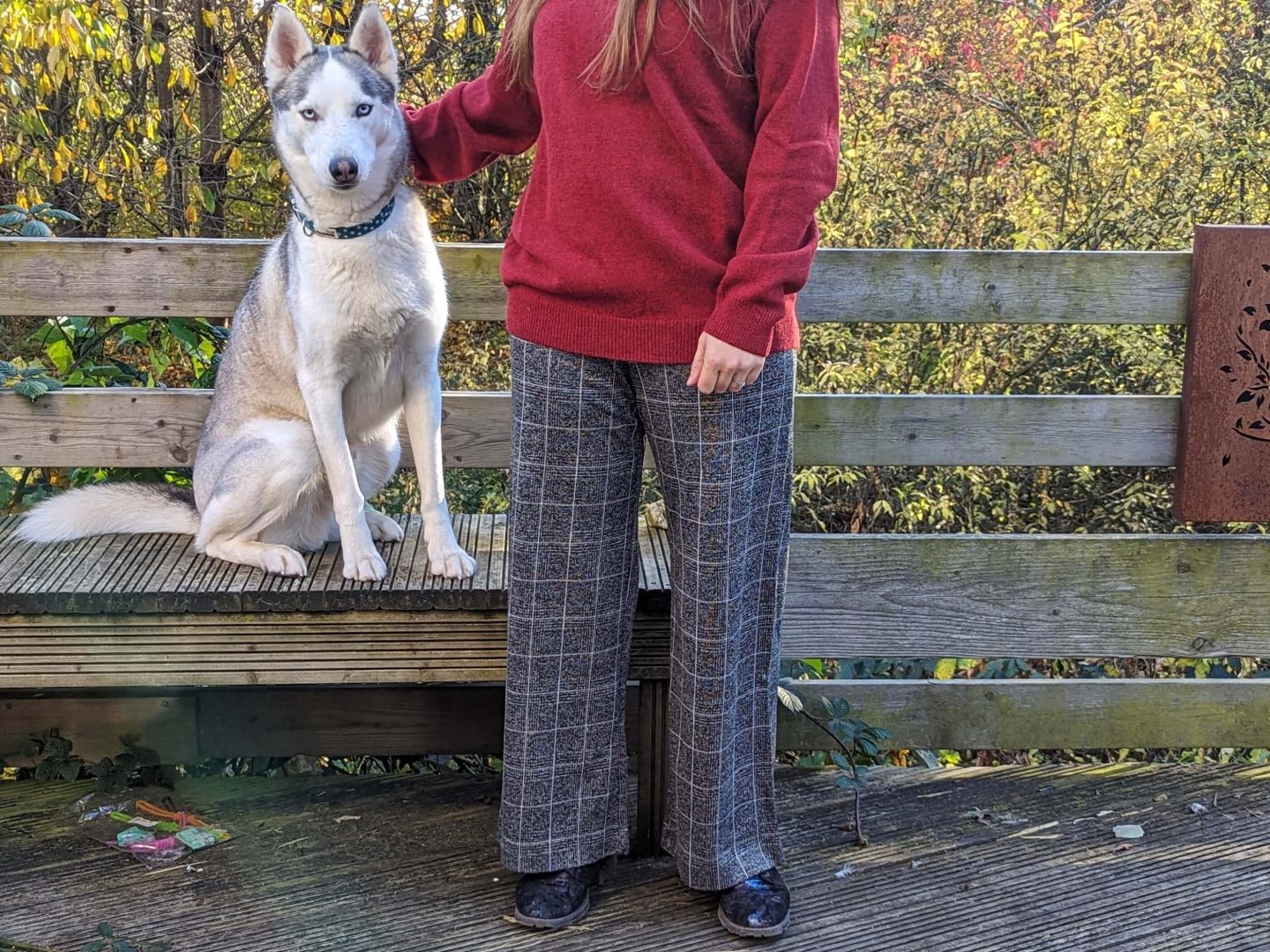 Natalie wearing grey chequed trousers standing next to Marko with autumn colours behind