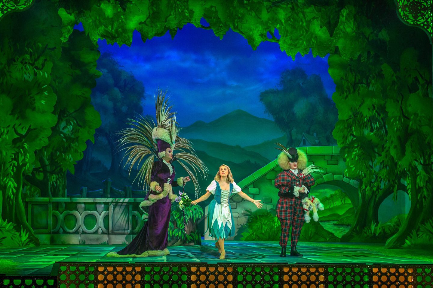 Cinderella  and the ugly sisters on stage with a green backdrop