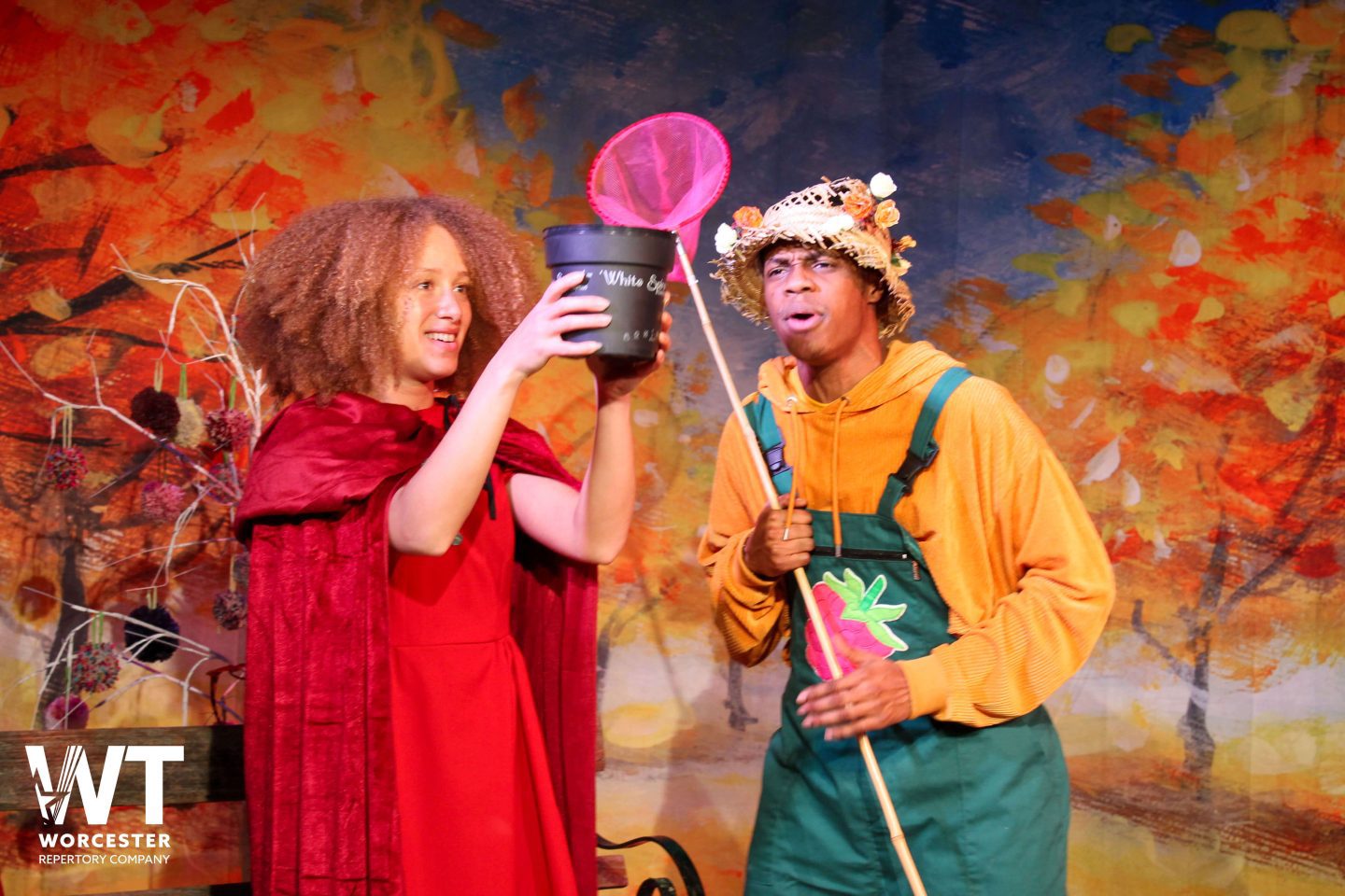 Little Red Riding Hood and a character in green dungarees on stage at The Swan Theatre Worcester
